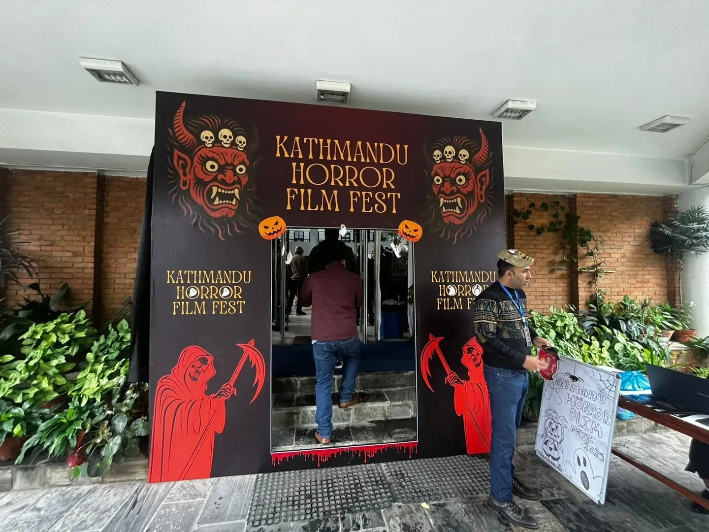 The Kathmandu Horror Film Fest entrance archway, painted with red masked deities and reapers, with an attendee walking through into the venue