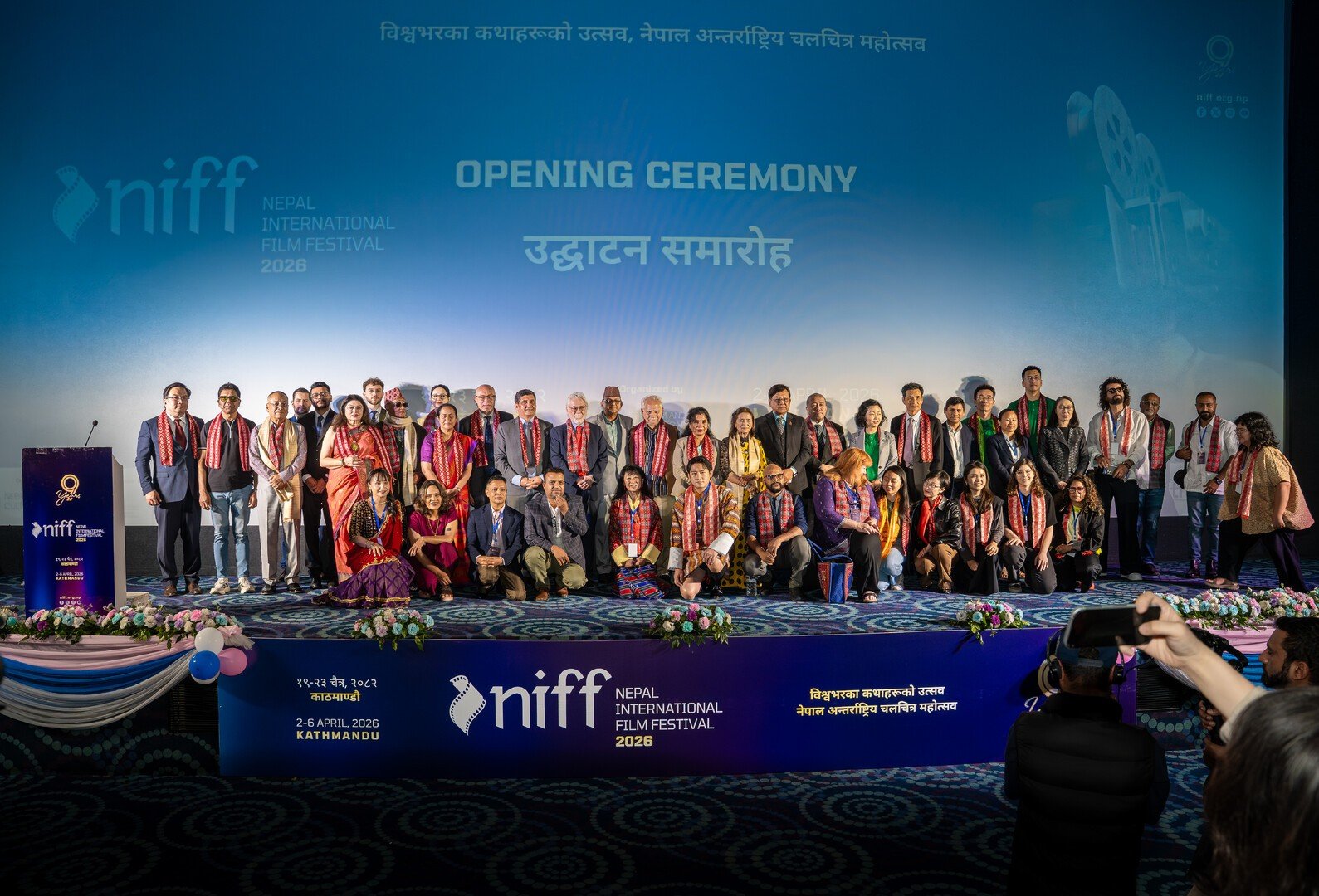 Delegates and guests in ceremonial scarves gathered on stage for the group photograph at the NIFF 2026 opening ceremony in Kathmandu